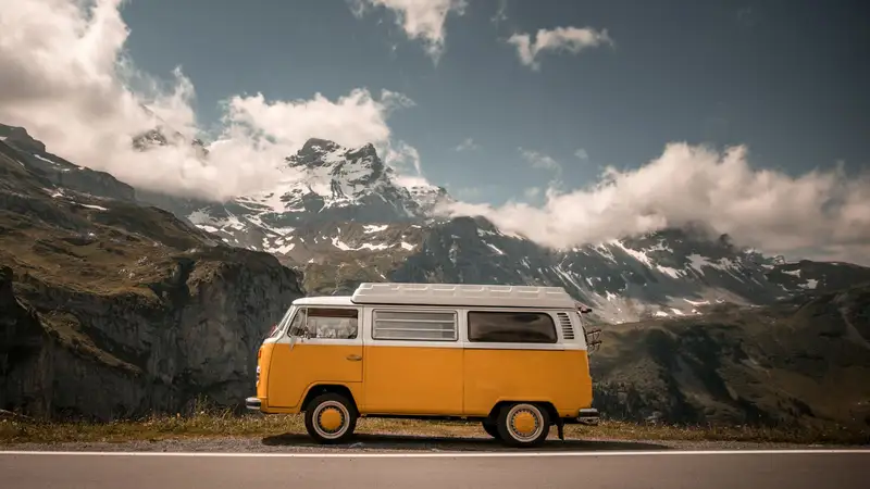 Furgoneta camper naranja en una carretera de montaña